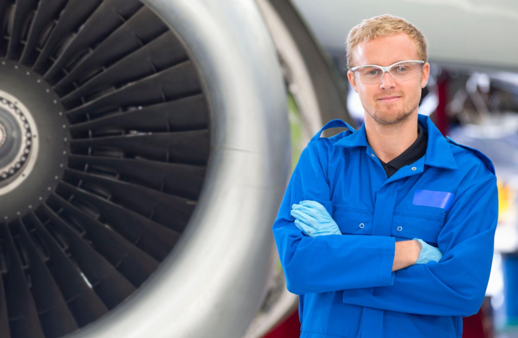 aviation engineer male wearing blue overalls near an aircraft turbine