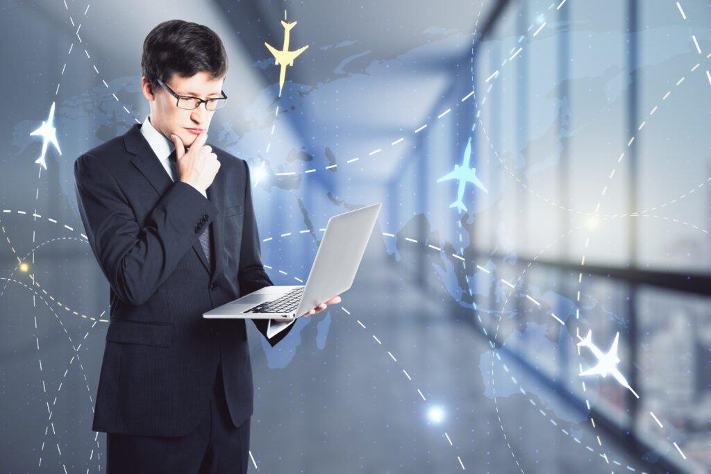 Person in business attire holding laptop in one hand, thinking, over a background depicting the planet and digitalized flight paths