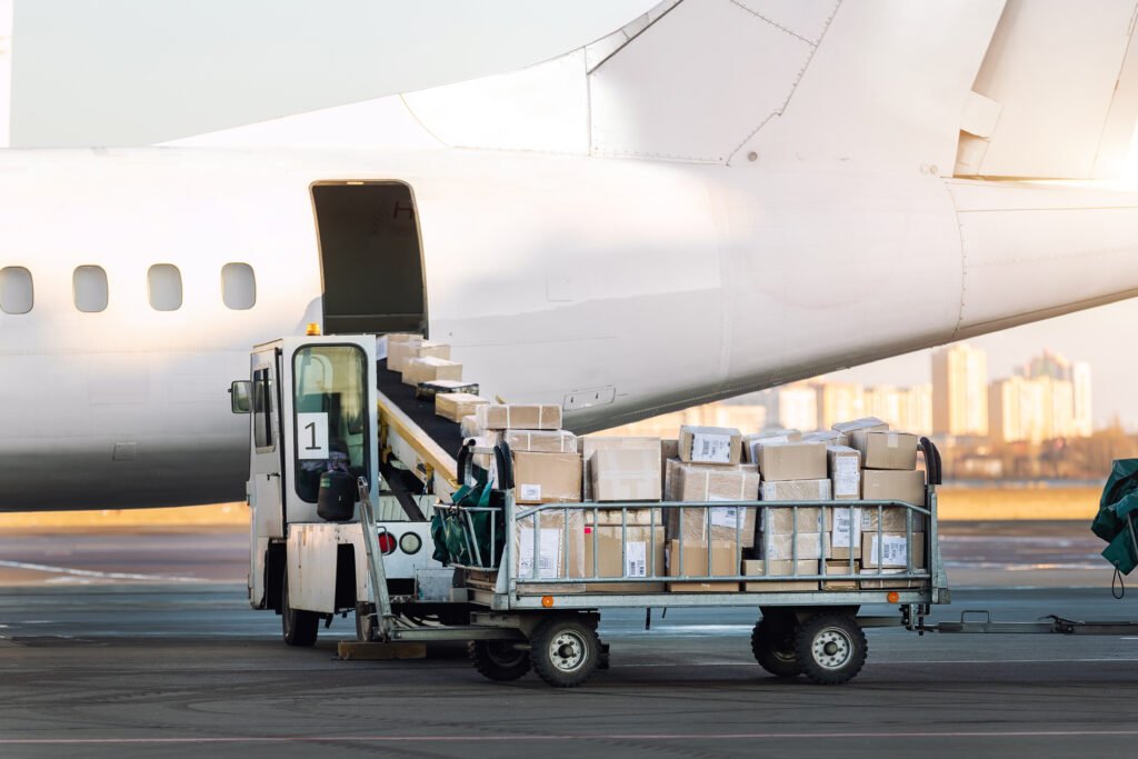 Close-up detail view of cargo cart trolley full with commercial parcels against turboprop cargo plane. Air mail shipping and logistics. Import export operations. Commercial charter flight service.