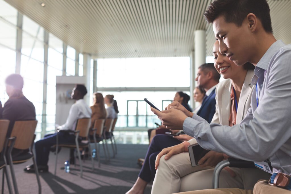 Side view of Asian business executives discussing over mobile phone during seminar in office building. Hiring Aviation Professionals