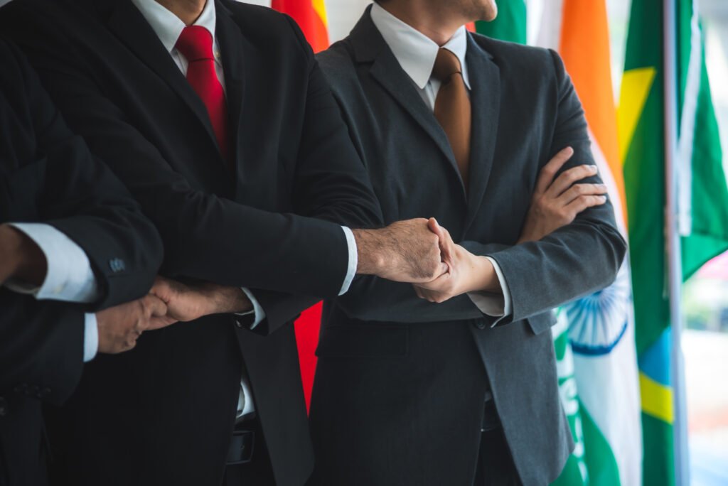 Business people shake hands, international flag background. Board-Level Internal Investigations.