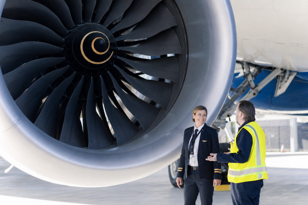 Pilot and ground crew member standing beside a commercial aircraft engine during a maintenance inspection. Green Aviation Jobs.