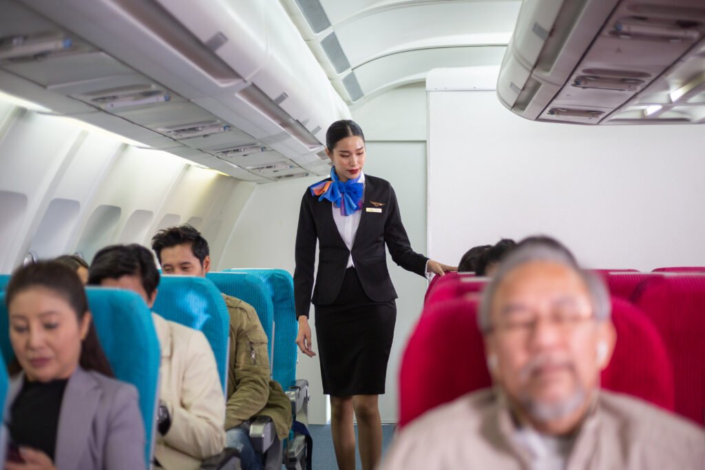 air hostess walking along the airplane aisle checking security on passenger sitting at seating before flight departure. flight attendant recruitment.